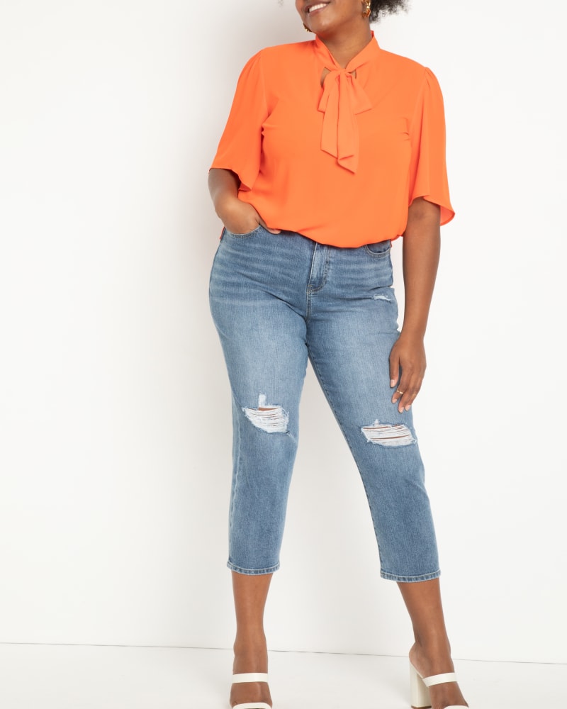 Front of a model wearing a size 14 Zoey Bow Blouse With Flutter Sleeve in Orange by ELOQUII. | dia_product_style_image_id:206720